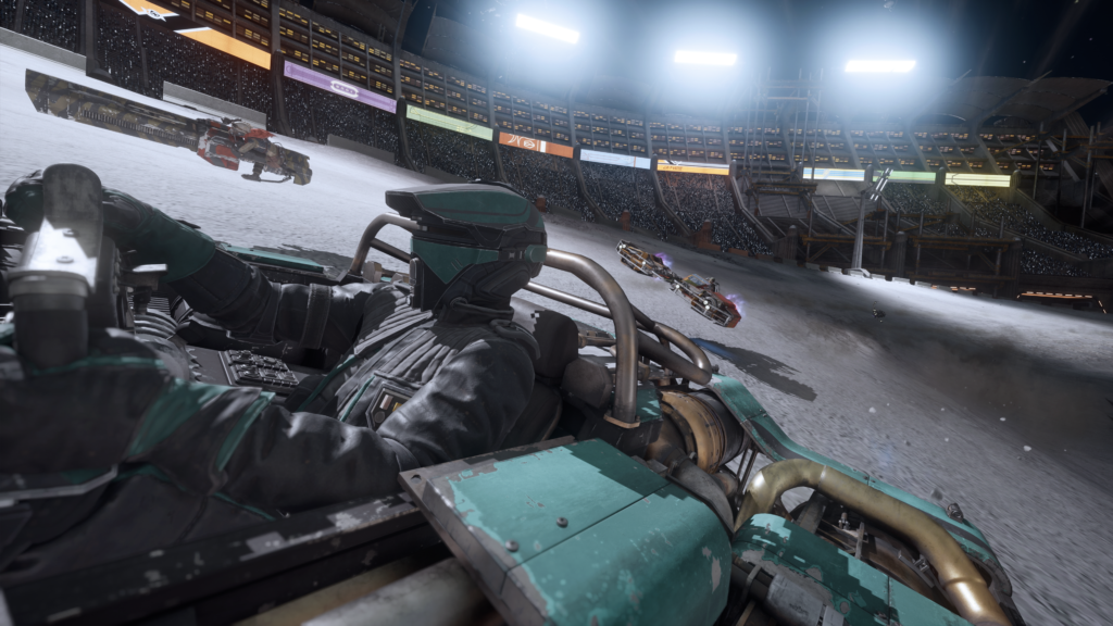 A pilot in a teal-and-black helmet sits in the cockpit of a vehicle during a race inside a large, illuminated stadium arena. Other vehicles speed along the track beside crowded grandstands under bright floodlights.